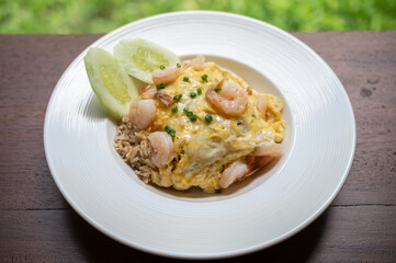 Close-up of seafood fried rice serving on wooden table. Thai fried rice is typical of central Thai cuisine. It normally contains meat (chicken, shrimp, pig), egg, onions, garlic etc.