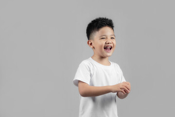 Portrait of happy joyful beautiful Asian little boy on gray background