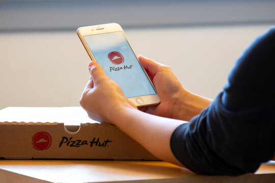 Calgary, Alberta. Canada Dec 4 2019: Woman holds an iphone plus with the Pizza Hut app on her hands. Pizza Hut release a new update of its app online pizza store .Illustrative