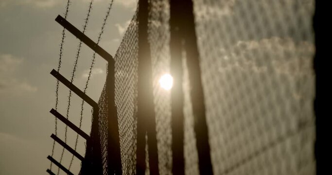 barbed wire netting close up at sunset beautiful sky , metal fence barrier , limits , freedom