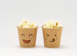 顔が描かれた紙コップにはいったポップコーン
