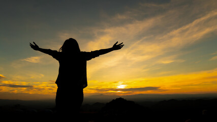 Fototapeta premium Silhouette of asian woman raise her arms looking at the mountain and enjoy with beautiful nature with freshness and happiness
