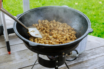 Process of cooking goulash in a cauldron outdoor.