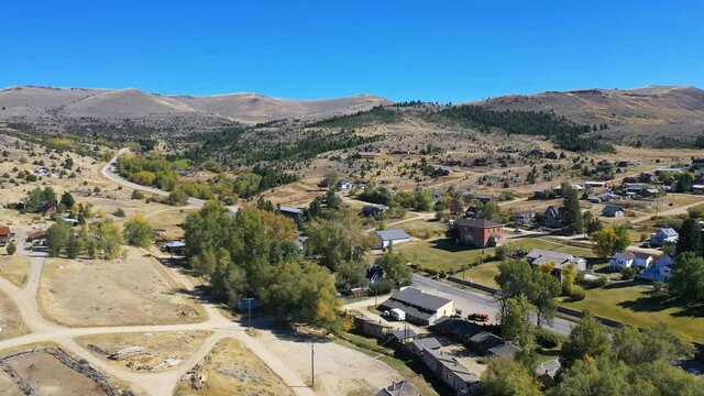Aerial-Flying over small town in the mountains of Montana under a clear blue autumn sky