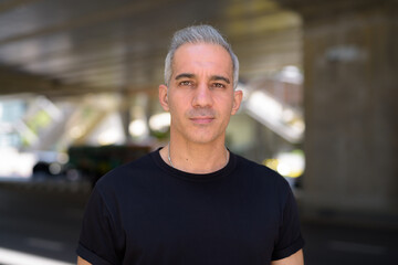 Fototapeta premium Face of handsome Persian man with gray hair in the city streets outdoors