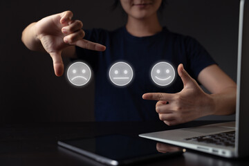 Woman using laptop and emoticon hologram effect.