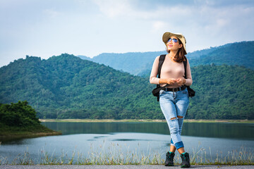 Asian woman traveler with backpack and looking at amazing mountains and forest