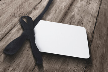 White label tag with black ribbon on wooden background