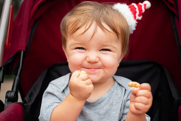 baby in the little santa hat sits in the stroller,