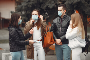 Young people are spreading disposable masks outside. The man and women are discussing virus problem and sharing respirators.