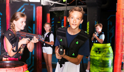 Portrait of teenager boy with laser gun having fun on dark lasertag arena..