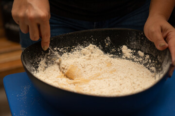 hands of a woman straining flour for a cake