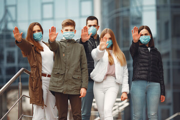 People wearing protective masks are showing stop sign by hands.