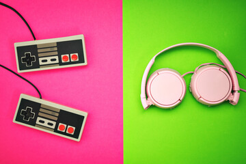 retro console and controls and headphones on fuchsia and green colors background