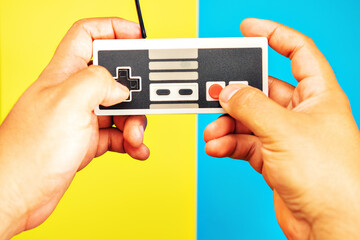 man hands with retro console and controls and yellow and blue colors background