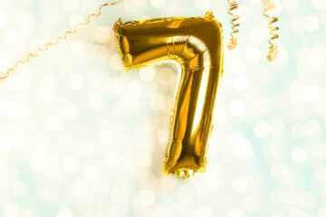 Decoration for seven birthday party. Golden balloon in form of 7 number on blue background....