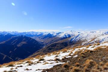Snow topped mountains landscape view with dry fields around in Queenstown, New Zealand.