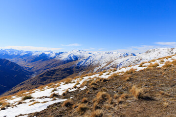 Snow topped mountains landscape view with dry fields around in Queenstown, New Zealand.