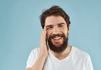 Fototapeta premium Handsome man with a beard on a blue background white t-shirt portrait