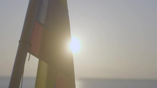 The sun is behind a flag of Ecuador or Colombia with the colors yellow, blue and red. The sun is setting or rising.