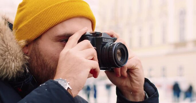 Close up of happy caucasian photographer making photo of new city standing outdoors in winter time. Hobbies.