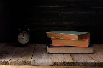 Old books and alarm clocks are placed on the old wooden table.