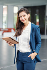 Portrait of beautiful young businesswoman standing with tablet computer and looking at camera
