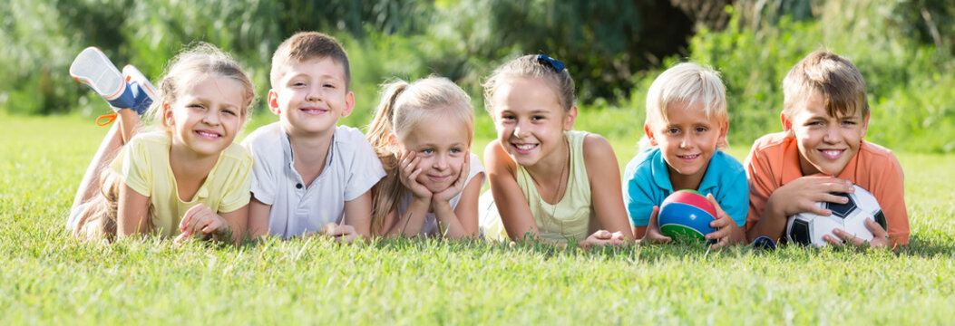 portrait of smiling american children lying on grass in park and looking happy .