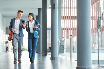 Fototapeta premium Smiling young businessman showing message on smartphone screen to his excited collegue when they are walking in office corridor