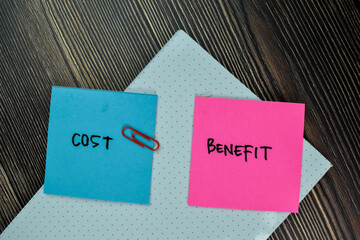 Cost and Benefit write on sticky note and isolated on Wooden Table. Finance Concept