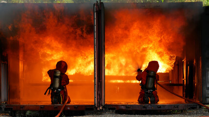 Firefighter fighting with flame using fire hose chemical water foam spray engine. Fireman wear hard...