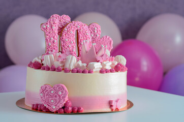 Pink and white cake with the number 10 and hearts on the table with balloons. Birthday.