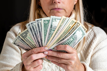 surprised female employee sitting at work and looking at dollar banknotes,  financial welfare concept