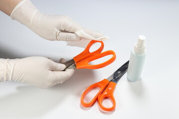 Cleaning staff clean scissors in office with alcohol spray and wipe out with clean paper. Corona Virus or bacteria infected protection from touching public object. 