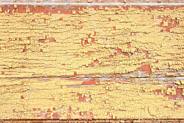 Texture of old wooden wall of abandoned building with peeled yellow paint abstract background.