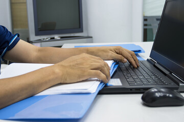 man hand holding files document and typing computer keyboard notebook in work office