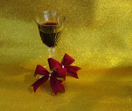Copa de cristal con vino tinto sobre fondo dorado diamantado y dos mo&ntilde;os aterciopelados en color guindo 5