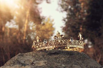 mysterious and magical photo of gold king crown in the England woods over stone. Medieval period concept.