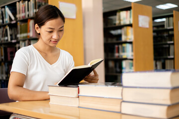 Young Asian women are searching for books and reading books on the tables and aisles of the college libraries to research and develop their academic and education self