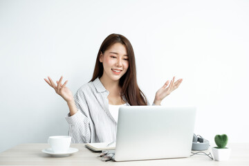 Video call, a young Asian woman communicates via online video long distance, looking at the digital laptop screen, happily greeted with a friend