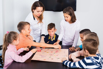 Fototapeta premium Boys and little happy girls playing at board game indoors
