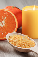 Wooden spoon with yellow sea salt and a cut orange