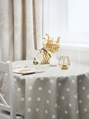 table setting.round table by the window with a light tablecloth. beige plate on the table with Cutlery, top view.