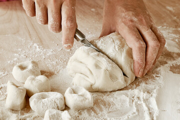 Fototapeta na wymiar woman chef cuts the dough with a knife, female hands in flour, female chef holds the dough, female hands with a knife in flour