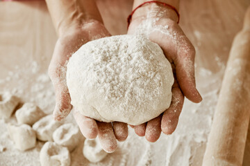 the cook is holding the dough, the baker's hands are holding the dough, female hands are in flour