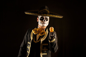 Mexican charro holding a candy skull in his hands on day of the dead