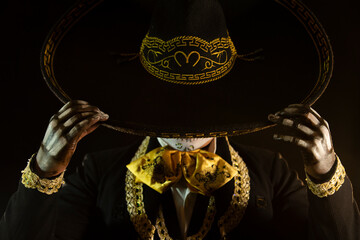 mexican charro holding his black hat