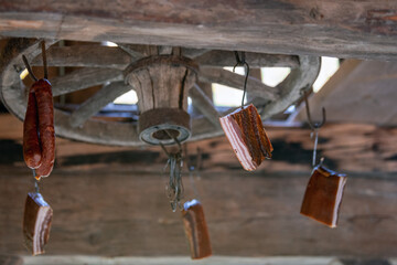 Alte Speisekammer: an einem Wagenrad unter der Decke aufgehängter Speck und Würste