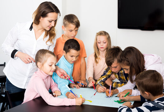 Smiling team of elementary age children drawing on one sheet