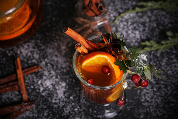 mulled wine tea with cinnamon and orange stands on a dark background